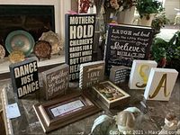 Multiple wooden inspirational blocks displayed on a table near a fireplace, including a block with the text "Mothers hold children's hands..." and others with motivational sayings, plus letter blocks S and A.