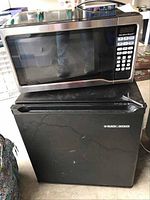 Hamilton Beach microwave placed on top of Black & Decker mini refrigerator, showing overall appearance and size relation.