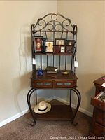 Overall view of the metal and wood bakers rack with items on the shelves and top surface.