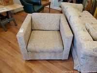 Front view of the tweed armchair showing the cushioned seat, backrest, and armrests with fabric texture.