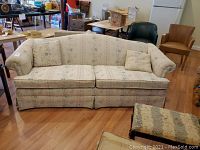 Front view of the upholstered sofa showing floral pattern and two cushions.