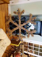 Full view of the large outdoor snowflake light display made from straw-like material with blue lights.