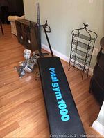 Total Gym 1000 workout bench and frame angled photo showing padded black bench with light blue logo and vertical support bars.