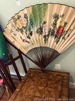 Peacock decorative wall fan hanging on wall over the coffee table