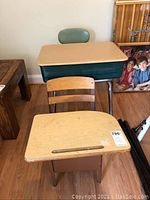 View of both vintage school desks showing green metal desk with cushioned backrest and smaller wooden desk with chair.