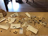 Wide shot showing many achievement pins spread on a wooden surface with some in envelopes or mounted on backing.