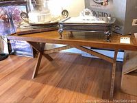 Full view of the wooden table with a silver tray and items placed on top, showing table surface and legs