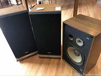 Pair of Fisher speakers with black grills and wood veneer sides, and Pioneer speaker without cover showing drivers.