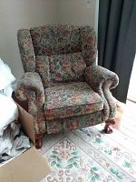 Front-right-angle view showing floral upholstery, rolled arms, padded wings, and wooden feet.