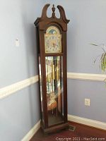 Full view of tall wood and glass grandfather clock showing front and side profile.