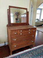 Front view of antique wood dresser with attached mirror showing all drawers and hardware.