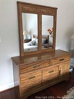 Front view of wooden dresser with matching mirror showing the oak finish, drawer pulls, and mirror panels.