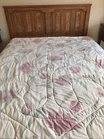 Full view of the bed with floral patterned mattress cover showing the wooden headboard and part of the mattress.