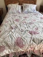 Bed made with floral comforter, pillows, and pillow shams showing full bed setup