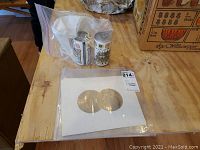 View of two Elvis decal art sheets in protective white backing and two cylindrical collectible cans in plastic bag on wooden table