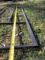 Close-up photo showing the full length of a metal garden panel laid on grass with a measuring tape showing approx 74 inches long.