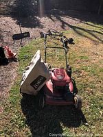 Front angle of red Toro push mower with fabric leaf collection bag attached