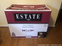 Photo of the boxed Estate by RSI Vanity Cabinet showing dimensions 36"W x 18"D.