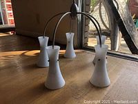 Chandelier shown on wooden floor fully assembled, view of all five frosted glass shades and metal arms