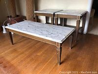 Full view of the coffee table in front of two matching side tables, showing the marble top and wooden legs.
