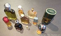 Overview of 10 vintage cologne and perfume bottles clustered together on surface, various sizes and shapes, mostly yellowish liquid inside.