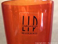 Close-up of LIP Murano label on orange glass flute