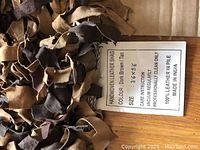 Close-up photo of the rug's label showing size (3'6" x 5'), color (Dark Brown tan), care instructions (vacuum regularly, professional clean only), material (100% leather in pile), and origin (Made in India).