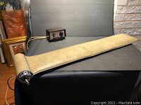 Full view of beige padded vibrating massager with motor housing and long cord, with separate control box in background