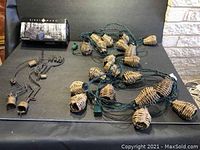 Sightmark Twilight DNV digital night vision monocular box, Kokopelli metal wind chimes, and pineapple wicker string lights displayed on black surface.