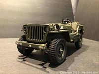 Front angle view of the detailed olive drab WWII Willys Jeep replica showing front grill, headlights, and tire tread.