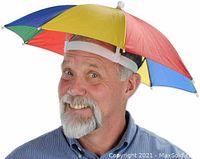 Man wearing rainbow umbrella hat with blue, yellow, red, and green panels and white adjustable headband