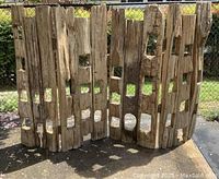 Front view of two hinged wooden panels with multiple rectangular and square cutouts, showing rustic texture and natural wood wear.