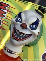 Close-up of Evil Clown Squeak Hammer toy with grotesque clown face, red nose, blue eye markings, and small black hat