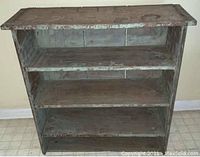 Front view of the shelving unit showing 4 shelves with worn distressed green paint finish and visible aging marks