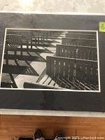 Photo of a black and white photograph showing angled wooden chairs casting shadows, featuring light and shadow interplay, titled 'Light, Shadows and Angles'
