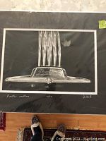 Close-up photo of black and white image of Pontiac car emblem, signed and numbered by artist John Poole on mat with double mat border