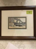 Overall view of framed print with dark wood frame and double matting on a marble surface.