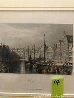 Framed etching showing a canal scene in Ghent with moored sailing boats and prominent brick buildings along the waterfront under a cloudy sky.
