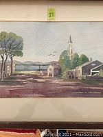Watercolour painting framed with dark wood and single mat showing Quebec landscape with buildings, trees, and church steeple. Artist signature present.