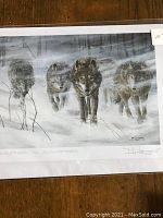 Four wolf art prints laid out showing realistic wolves walking through snow in a winter forest scene