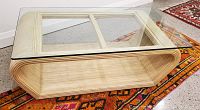 Angle view of clear glass top resting on rattan base placed on patterned rug
