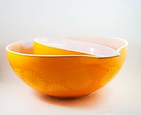 Side view of larger and smaller orange Daisy Pyrex Cinderella mixing bowls stacked