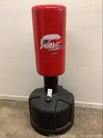 Full view of red punching bag mounted on black water-fillable base