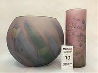 Both decorative art glass pieces shown together: pink tall cylinder vase and round pastel design bowl