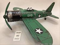 Front-left angled view of the green metal airplane model showing rivet details, propeller, cockpit, and star insignias.