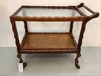 Front-facing photo of vintage wooden tea service cart with glass top and wooden bottom shelf, showing overall condition and design.
