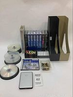 Lot contents showing portable hard drive, VHS tapes, cassette tapes, CD-R, and storage holders