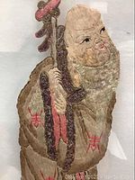 Close-up of the Star of Longevity figure embroidery showing detailed stitching on the face, beard, and staff.