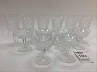 Full set of 12 crystal stemware arranged with 6 taller wine glasses and 6 shorter champagne coupes, showing diamond cut pattern on all glasses.