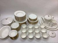 Full set from front showing stacked plates, bowls, cups, teapot, shakers, creamer, serving platters and bowls